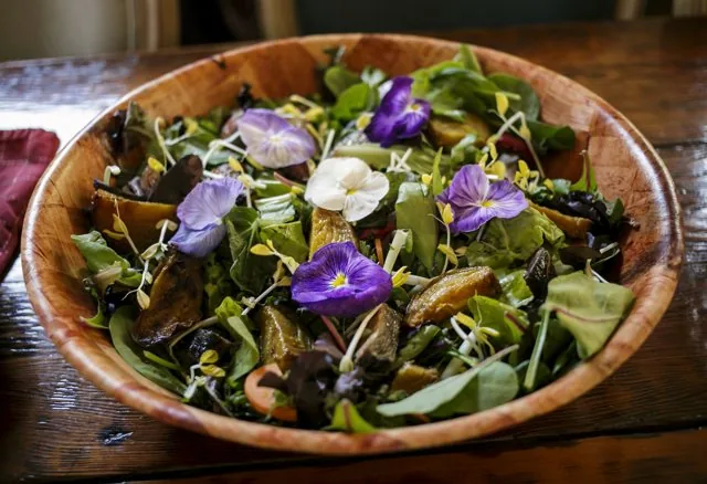 A salad bowl finished with edible flowers